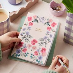 a person holding a notebook with flowers on it