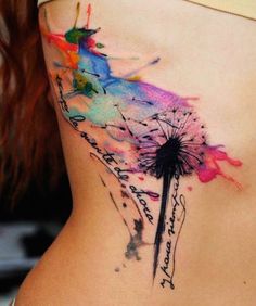 a watercolor tattoo on the side of a woman's stomach with a dandelion