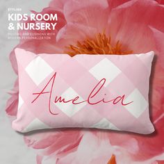 a pink and white pillow with the word amelie on it next to a large flower