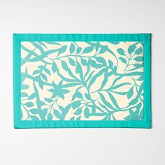 a teal and white placemat with leaves on it, against a white background