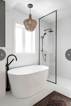 a white bath tub sitting under a window next to a shower