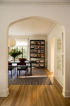 an archway leads to the dining room and living room in this modern style home with wood flooring