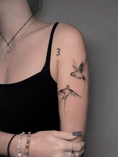 a woman's arm with tattoos on it and a bird flying over her shoulder