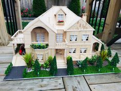 a doll house made out of wood with plants and flowers on the front porch area