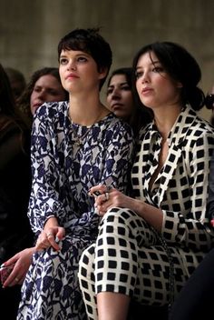 two women sitting next to each other at a fashion show