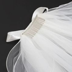 a bridal comb with white tulle and ribbon on it's headband