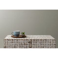 a coffee cup sitting on top of a wooden table next to a plate with a plant