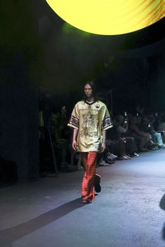 a man is walking down the runway at a fashion show