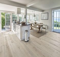 a kitchen with white cabinets and an island in the center is surrounded by chairs and tables