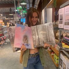 a woman is holding up some pictures in her hands