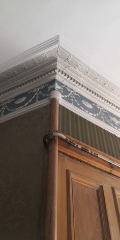 the corner of a door with an ornate design painted on it's trimming