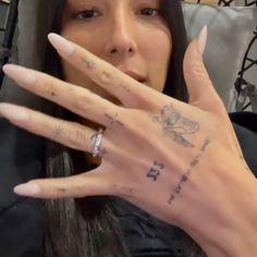 a woman with tattoos on her fingers and hand is making a gesture to the camera