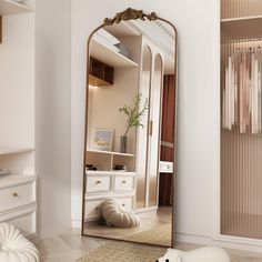 a mirror sitting on top of a wooden floor next to a white dresser and chair