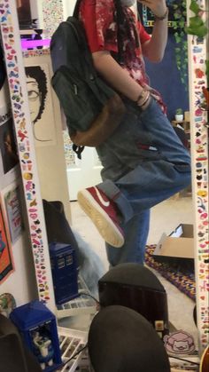 a man taking a selfie in front of a mirror with his hat and backpack