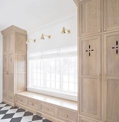 an empty room with white and black checkered flooring on the floor, cabinets in the wall