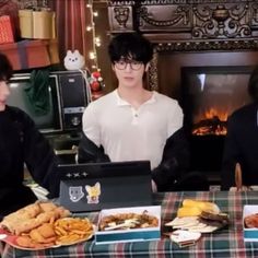 three people sitting at a table with plates of food in front of the fire place