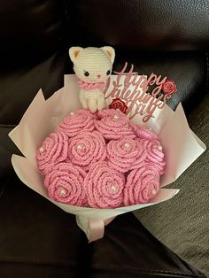 a teddy bear sitting on top of a bouquet of pink cupcakes in a paper wrapper