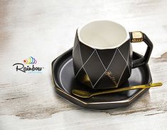 a black and white coffee cup sitting on top of a saucer next to a spoon