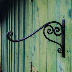 an iron hook on the side of a green building