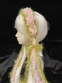 a white mannequin head wearing a green and pink hat with flowers on it