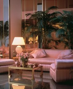 a living room filled with pink couches next to a table and two lamps on top of it