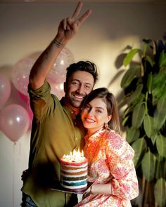 a man and woman are holding a cake