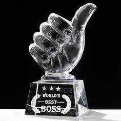 a clear glass trophy with a hand holding the world's best boss