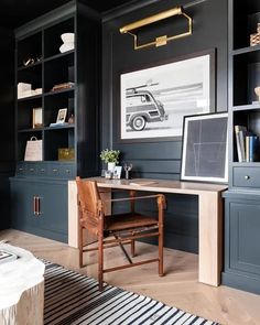 an office with black walls and wooden floors, built in shelving units is shown