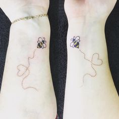 two small tattoos on both wrists with hearts and bees attached to the wristbands