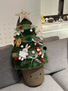 a small christmas tree sitting on top of a couch next to a stuffed animal toy