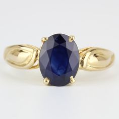 a yellow gold ring with an oval blue sapphire in the center and leaves around it