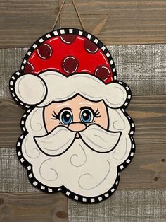 a wooden sign with a santa clause on it's face and polka dots around the eyes