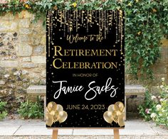 a black and gold celebration sign sitting in front of a stone wall