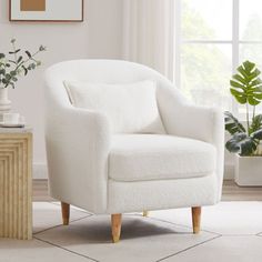 a white chair sitting in front of a window next to a table with plants on it