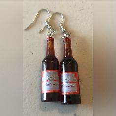 two beer bottles are hanging from silver earwires