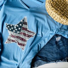 an american flag t - shirt is laying on top of denim shorts and a straw hat