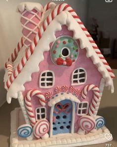 a pink and white gingerbread house with candy canes on it's roof