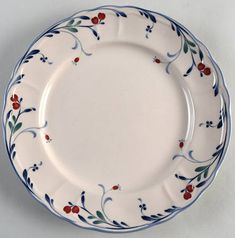 a white plate with blue trim and red flowers on the rim is sitting on a table