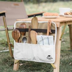 an outdoor picnic table with utensils and wooden spoons in a storage pocket