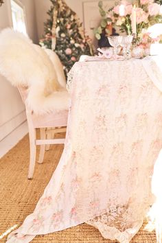 the table is set for two with pink flowers on it and a white chair next to it