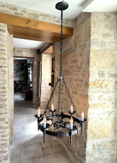 a chandelier hanging from the ceiling in a room with stone walls and flooring