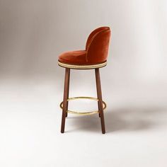 an orange velvet bar stool with gold trim around the foot rest and back rests on a white background