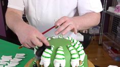 someone is decorating a green and white cake