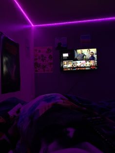 a tv that is on in a room with purple lights around it and people watching