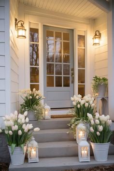 white tulips and candles are on the front steps of a house with lanterns