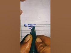 a person writing on a piece of paper with a pen in their left hand and another hand holding a green marker