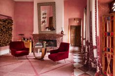 a living room with two red chairs and a fire place in the middle of it