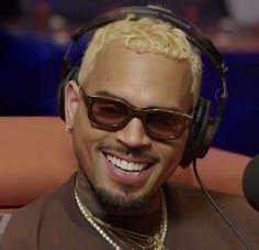 a man wearing headphones and sunglasses sitting in front of a microphone with a smile on his face