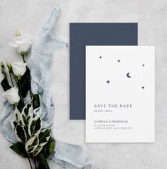 a white and blue wedding save the date card next to some flowers on a table