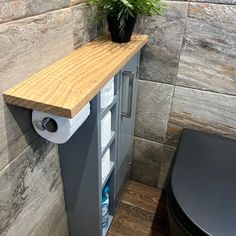 a bathroom with a toilet and a plant on the shelf next to the trash can